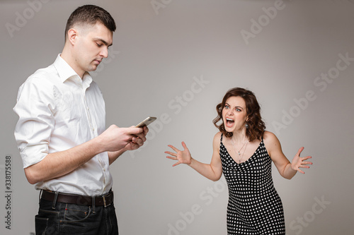 Beautiful young woman shouting at her boyfriend while he is using his mobile phone. Gadget addiction concept called phubbing. Relationship problems. photo