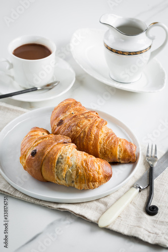 Breakfast with coffee and croissant in white cup and plate on marble background. Healthy homemade pastry  copy space