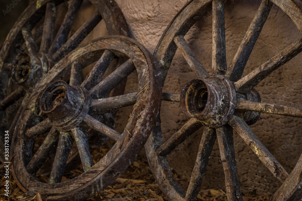 Wooden wheels resting on the wall. Close up of wooden carriage wheels resting on a house wall.