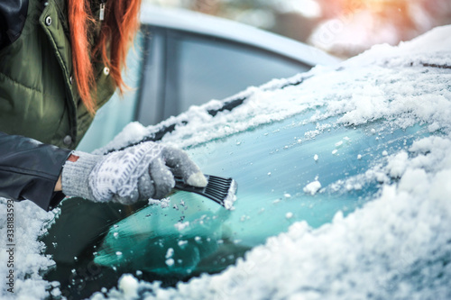 Clean car window from snow in winter time. Windshield cars cleaning.