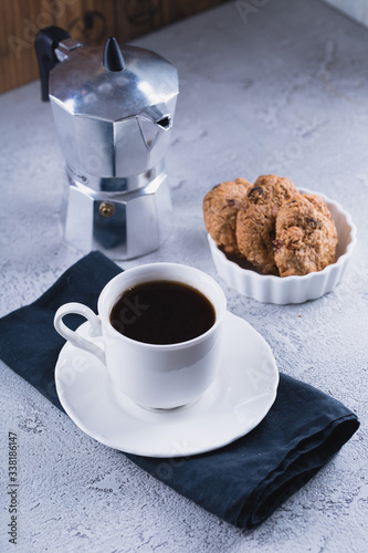 White cup of coffee with oatmeal cookies and coffee maker, breakfast concept, selective focus