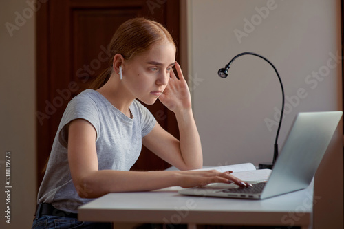 Young girl listens attentivly online webinar with laptop computer at home. Education, technology and home project photo