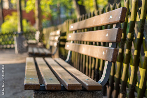 Wooden bench in a park with a wooden fence behind it from the side