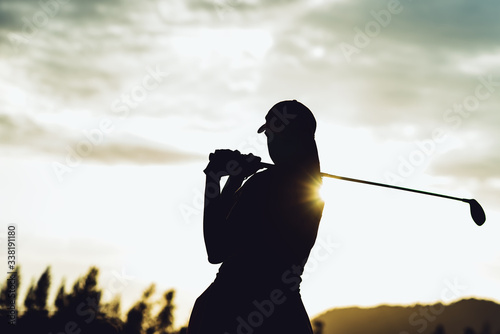 Silhouette of  young professional female golf player hit sweeping and keep golf course doing golf swing,she does exercise for relax time