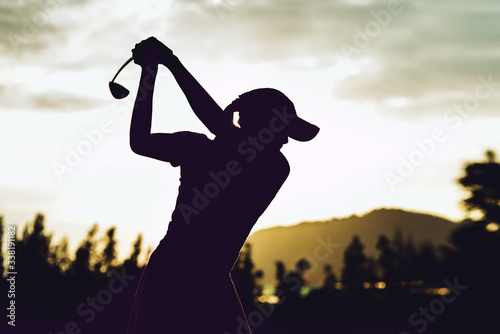 Silhouette of  young professional female golf player hit sweeping and keep golf course doing golf swing,she does exercise for relax time