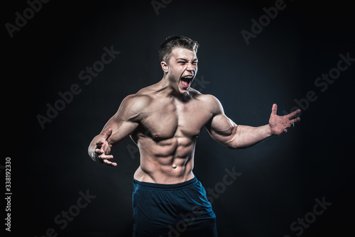 Sexy young athlete posing on a black background in the Studio. Fitness, bodybuilding