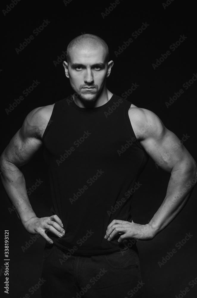 Naklejka premium Sporty guy posing in the Studio on the background. Sports, beauty, black and white photography