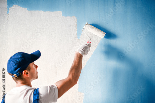 Painter painting a wall with paint roller. photo