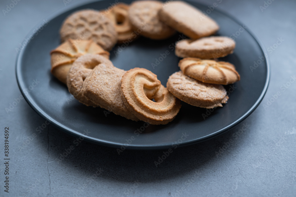 Homemade butter cookies on a grey plate on concrete background. Danish cookies. Close up view. Homemade butter cookies on a grey plate on concrete background. Danish cookies. Close up view.