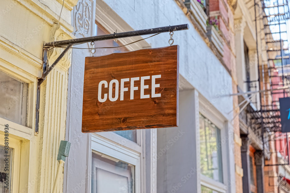Fototapeta premium Wooden coffe sign on a metal carrier at a facade
