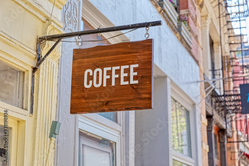 Wooden coffe sign on a metal carrier at a facade