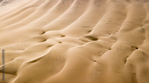 Aerial top-down view of sand dunes. Sand dunes create abstract shapes during the day light. Wind formations. © Katarzyna