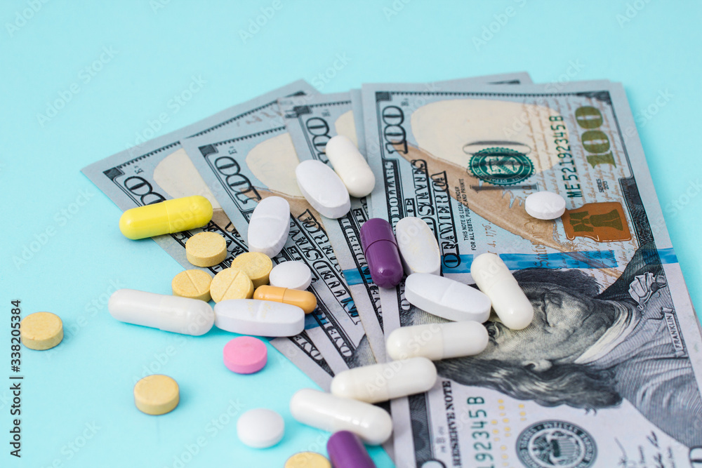 Healthcare cost concept. US Dollars with medicine pills. White pills spilling from medicine bottle. High Cost of Medicine and Healthcare. US Dollar Medicine Healthcare cost concept. US Dollars with medicine pills. White pills spilling from medicine bottle. High Cost of Medicine and Healthcare. US Dollar Medicine