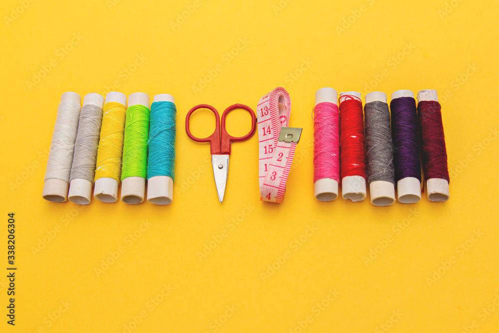 Thread, needles, scissors and meter on yellow background. tailoring set. sewing kit multi-colored. Thread, needles, scissors and meter on yellow background. tailoring set. sewing kit multi-colored.