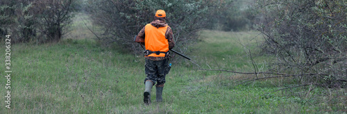 Hunter with a gun and a dog go on the first snow in the steppe, Hunting pheasant in a reflective vest