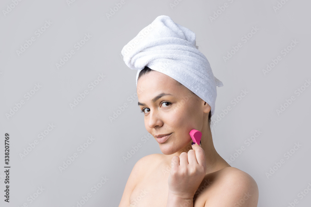 Beauty portrait of woman in white towel on head with a sponge for a body in view of a pink heart. Skincare cleansing eco organic cosmetic spa relax concept. Beauty portrait of woman in white towel on head with a sponge for a body in view of a pink heart. Skincare cleansing eco organic cosmetic spa relax concept.