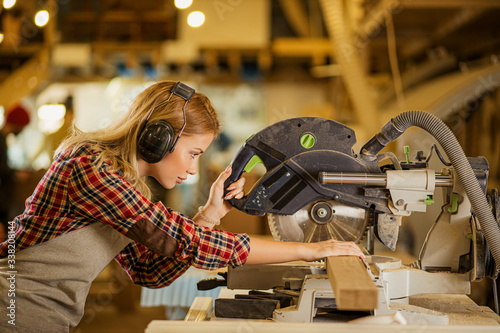 caucasian woman carpenter drives a circular saw, concentrated woman work in factory contrary to opinion that this is a man s job. feminism concept photo