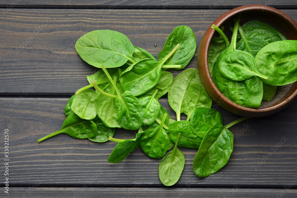 Spinach leaves in wooden bowl on dark wooden table background. Healthy vegan food trend. Vegan lifestyle concept. Top view. Spinach leaves in wooden bowl on dark wooden table background. Healthy vegan food trend. Vegan lifestyle concept. Top view.