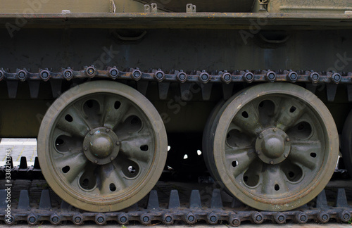 Military background lateral part of heavy armored vehicles. Heavier armament tracked armored vehicles close-up. At the bottom are powerful wheels and tracks, on top are elements of external equipment.