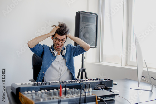 Workplace stress. Aggressive behavior Male music arranger hands composing song on midi piano and audio equipment in digital recording studio. Man produce electronic soundtrack or track in project at photo