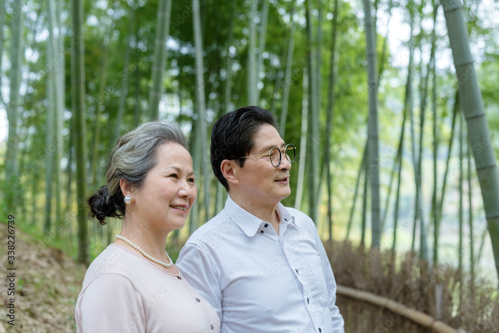 An elderly Asian couple walking in a bamboo forest An elderly Asian couple walking in a bamboo forest