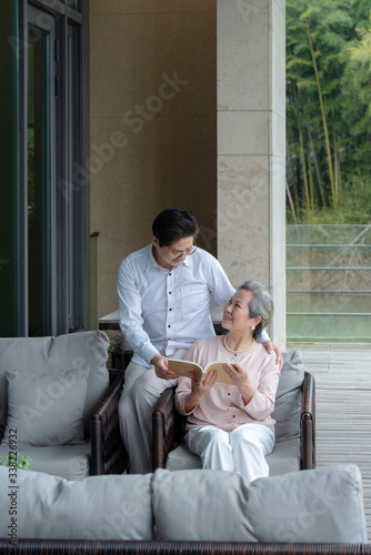 An elderly Asian couple reading a book