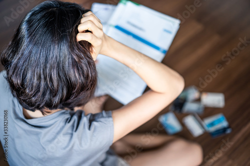 Top view of stressed young Asian woman hands holding the head trying to find money to pay credit card debt and all loan bills. Financial problem from coronavirus or covid-19 outbreak crisis concept. photo