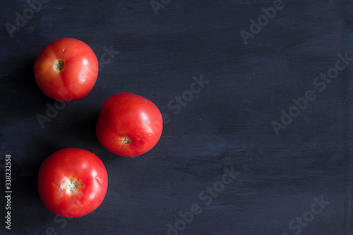Three tomatoes in a dark blue table