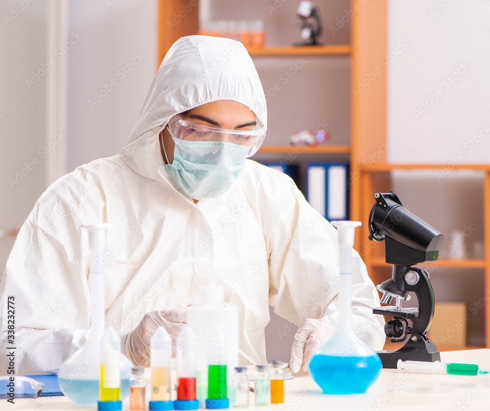 Young biochemist wearing protective suit working in the lab Young biochemist wearing protective suit working in the lab