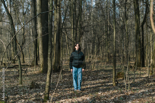 young woman standing alone in wild forest, self-isolation loneliness concept
