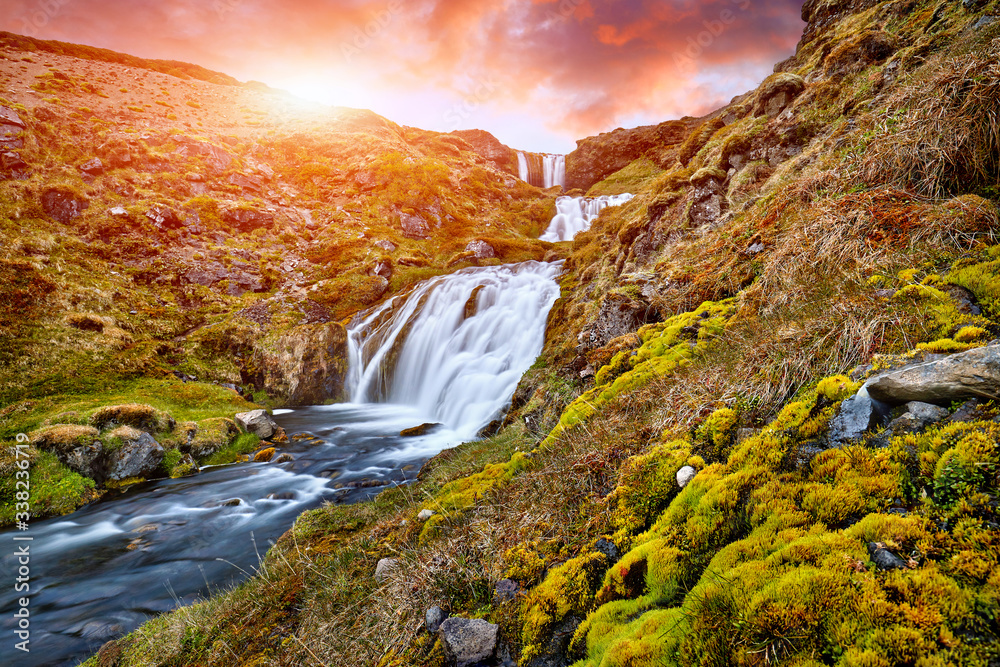 Sheep's Waterfall. Famous tourist landscape. Travel concept background. Dramatic summer sunrise, Iceland, Atlantic Ocean, Europe. Travel postcard. Amazing Sunset. Beautiful Sunrise. Virgin Nature.
