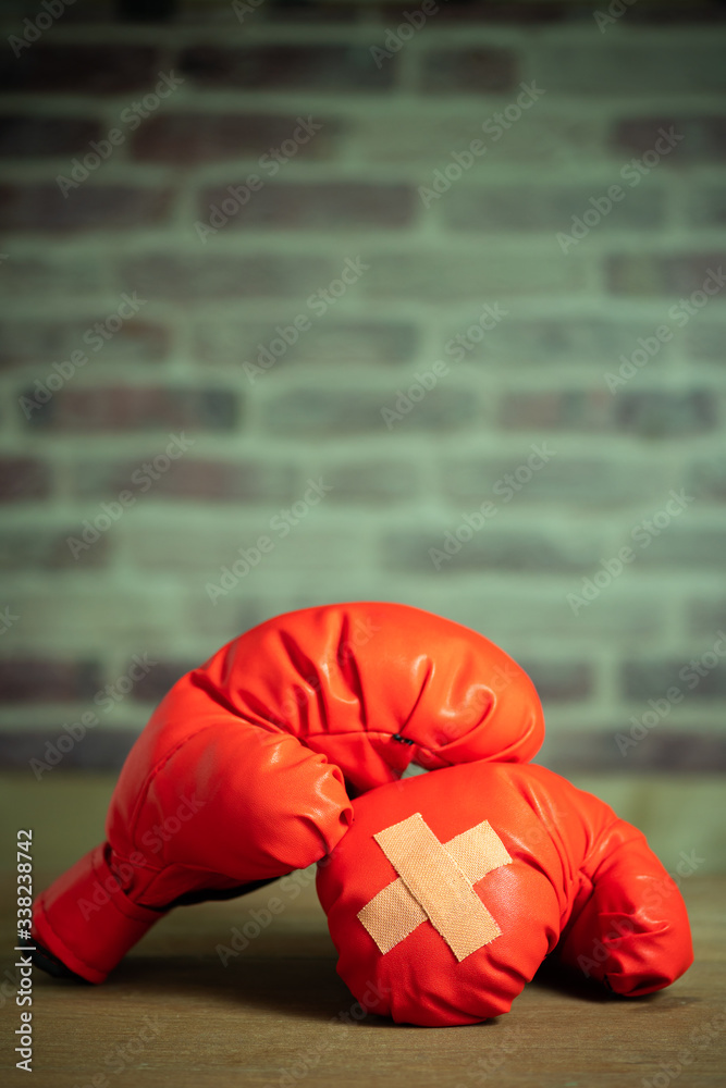 Red boxing gloves on wooden table and brick wall at the sport gym