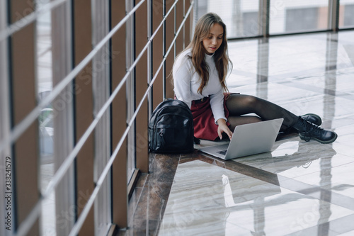 attractive girl sitting on floor with laptop and things in airport terminal or office. travel atmosphere or alternative work atmosphere.