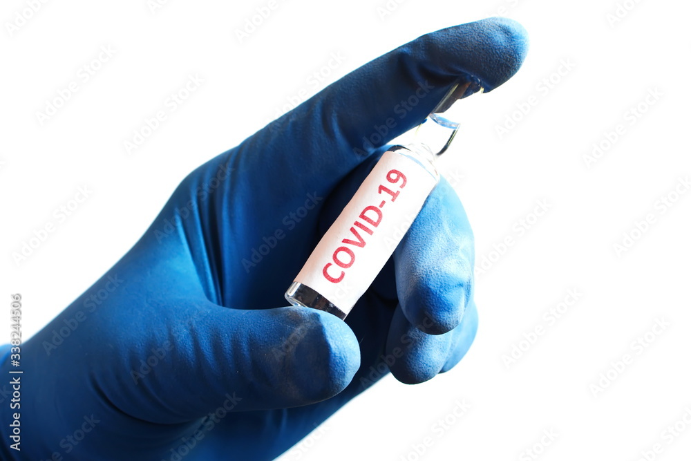 Concept on coronavirus global outbreak. Palm protected by rubber blue glove hold glass medical ampoule with the text covid-19 isolated on white background Concept on coronavirus global outbreak. Palm protected by rubber blue glove hold glass medical ampoule with the text covid-19 isolated on white background