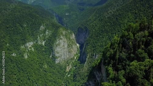 From great height Kodori Gorge Yupshar Canyon sheer high ancient cliffs mountain alpine natural epic landscape. Cumulus clouds blue sky Abkhazia Caucasus. Open space freedom. Green forest. Aerial 4k photo