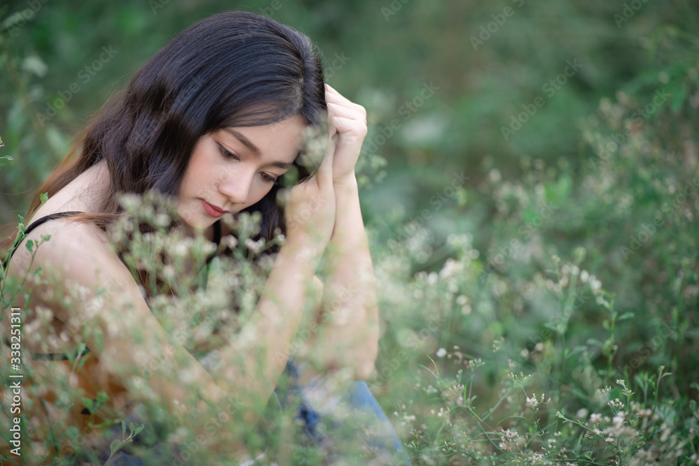 Portrait of sad woman sitting in field. Asian female feel lonely outdoor in park free from copy space. Portrait of sad woman sitting in field. Asian female feel lonely outdoor in park free from copy space.