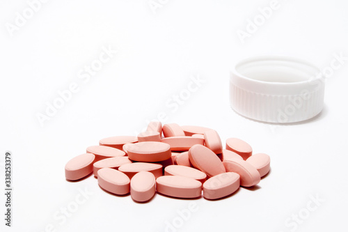 Pink pills and a bottle cap against a white background