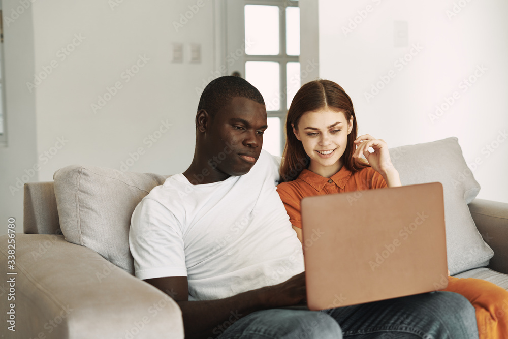 young couple sitting on sofa with laptop