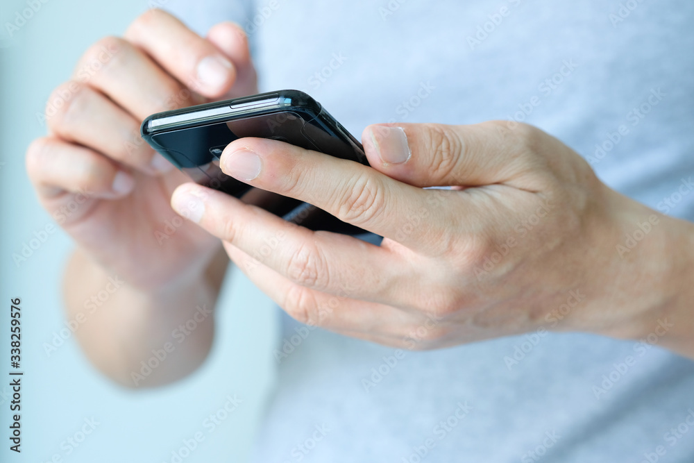 The young man's hand He is using a smartphone to connect with friends in the social network. The young man's hand He is using a smartphone to connect with friends in the social network.