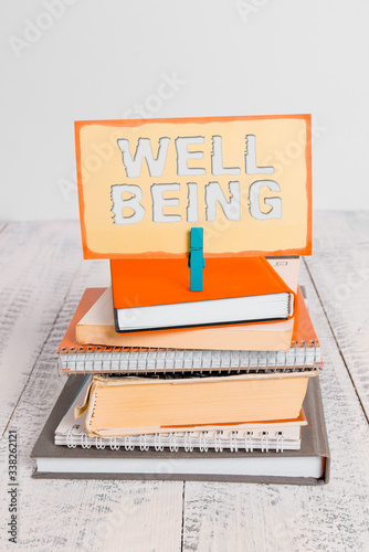 Handwriting text writing Well Being. Conceptual photo A good or satisfactory condition of existence including health pile stacked books notebook pin clothespin colored reminder white wooden photo