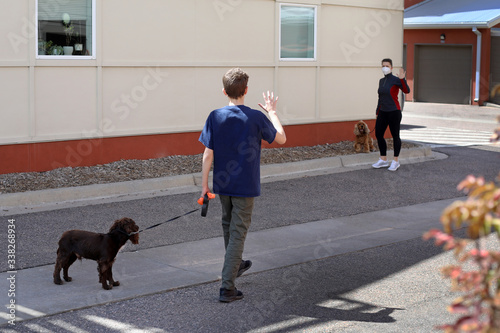 During the Coronavirus quarantine neighbors walking their pets greet each other keeping the social distance