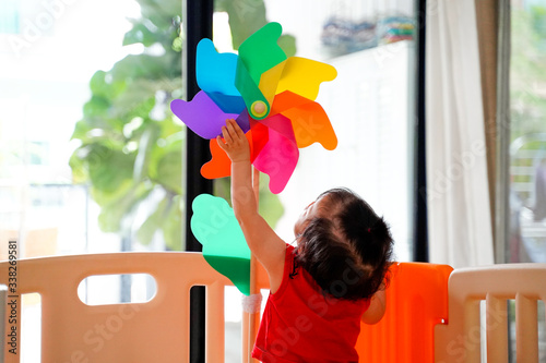 Happy baby with colorful  windmill ,toddler try to handle the windmill pin in partition at playroom ,home.