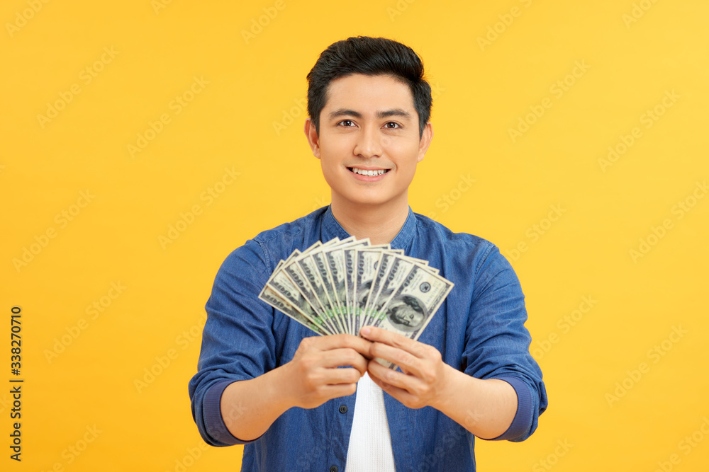 Astonished asian man holding bunches of dollars, lucky lottery winner Astonished asian man holding bunches of dollars, lucky lottery winner