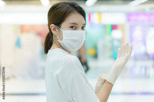 Woman protects herself from infection with the surgical mask and gloves, ready for shopping at supermarket after coronavirus pandemic.