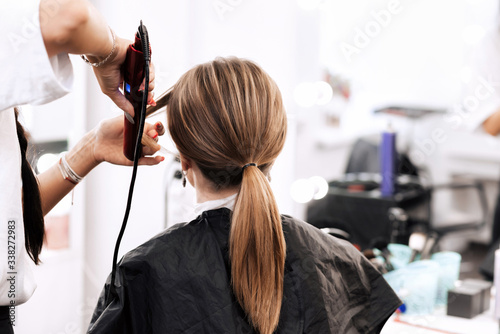 hairdresser does a tail hairstyle for a woman with long brown hair