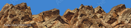 Mountain landscape. Close-up. The top of a mountain range against a clear blue sky. Panoramic. Low angle view. Wide banner with a beautiful view of the peak of the mountain range.