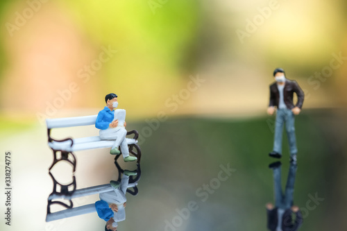 Miniature people : A man who wear mask to protect pollution, corona virus (COVID-19) sitting on the Bench. Traveler standing in front of house. Healthcare and Social distancing concept.