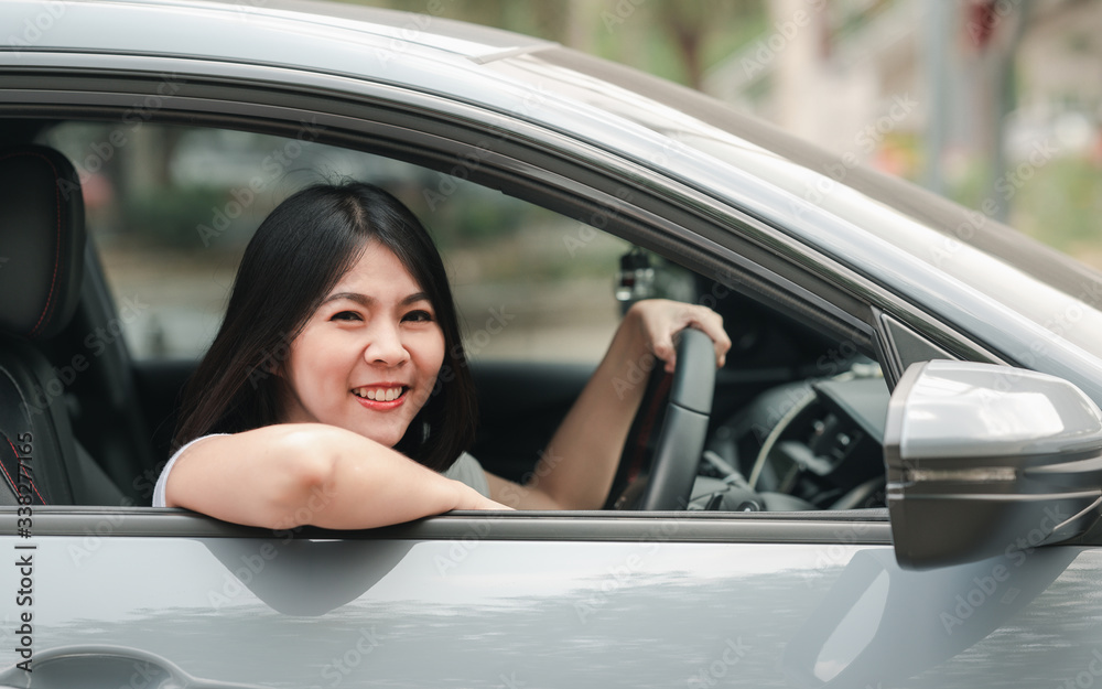 Happy smiling asian woman driving her new car with confident