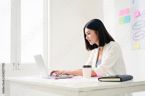 Concept of work from home. Young asian business woman working on computer laptop in office room with paperwork document on desk