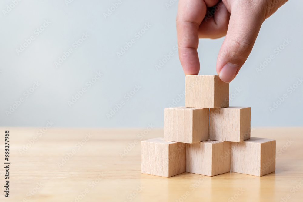 Hand arranging wood block stacking as step stair on top pyramid. Business concept for growth success process Hand arranging wood block stacking as step stair on top pyramid. Business concept for growth success process